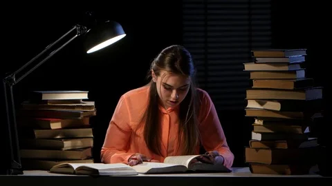 Girl reads and writes information in a notebook. Black background Stock Footage