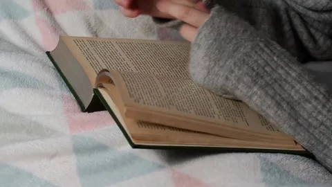A girl reads a book while lying in bed. Stock Footage 223371956