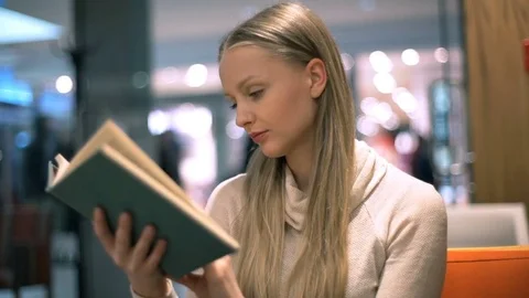 Girl receives message while reading book and texting back Stock Footage 70134136