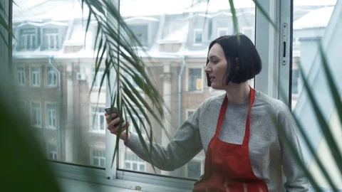 Girl in red apron smiling using smartphone showing photos to guy in greenhouse Stock Footage 87067183