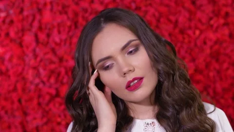 A Girl on a red Background is thinking about Something. Closeup Stock Footage 163468028