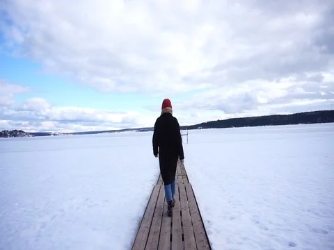 Girl in a red hat and coat goes on the pier Stock Footage