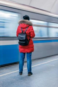 A girl in a red jacket with a backpack stands with her back on the Moscow sub Stock Photos