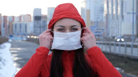 Girl in a red jacket puts on a protective mask. Stock Footage 128979809