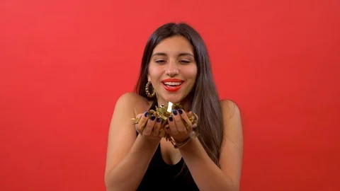 Girl with red lips blowing confetti at camera and posing over red background Stock Footage 109793653