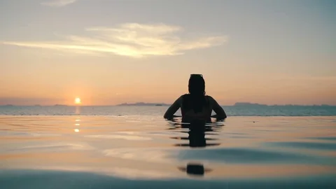 Girl relaxes in the pool at sunset Stock Footage 110185854