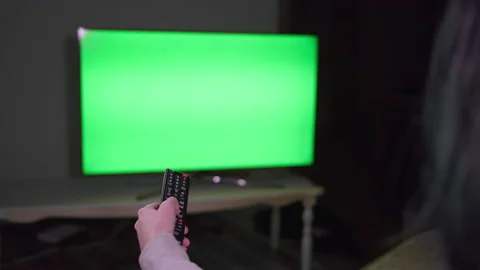 Girl with a remote control in her hand switches channels, sits Stock Footage 155309747