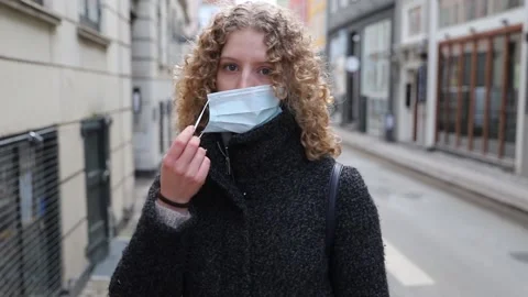 A girl removes the surgical mask she wears to protect herself from covid-19 Stock Footage