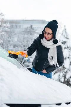 Girl removing snow from the car  Stock Photos