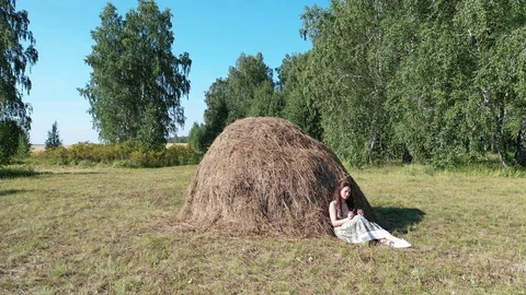 Girl resting by a haystack on a hot summer day Stock Footage 128350013