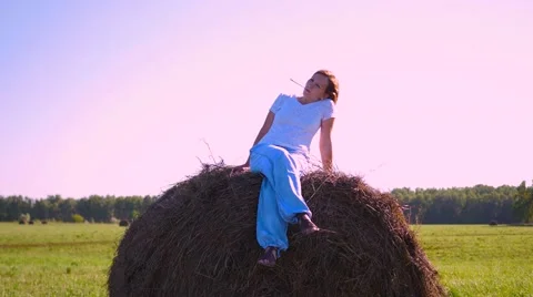 Girl resting on a haystack at sunset Vidéo 66243167