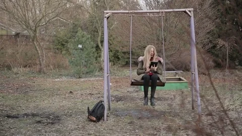 The girl is riding on a swing with a tablet Stock Footage 73259088
