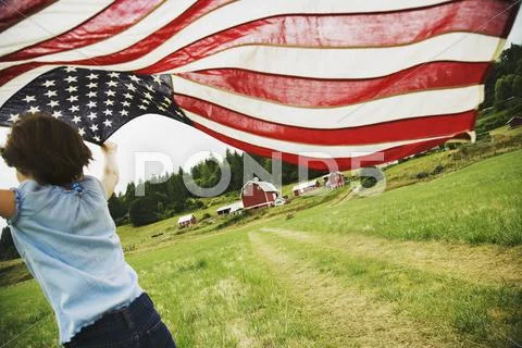 Girl running with American flag on farm Stock-Fotos