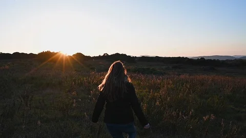 Girl running and jumping into the wild field nature at sunset Stock Footage 103790153
