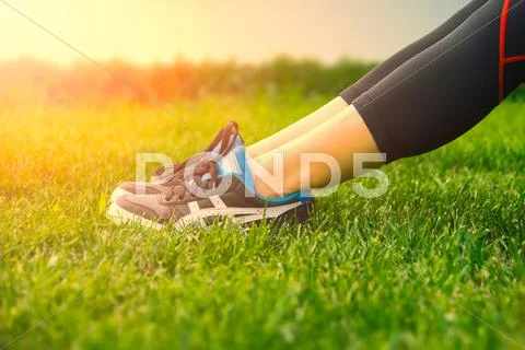 Girl running shoes closeup, green grass, woman fitness Stock Photos