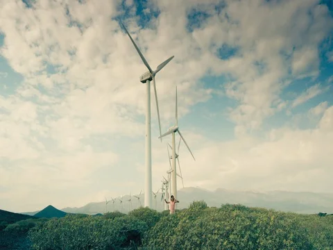 Girl running towards the camera under windmills with spinning blades Stock Footage 72948376