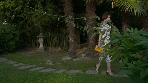 A girl runs along palm trees along a path of stones Stock Footage