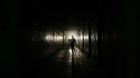 The girl runs away from the zombies along the corridor Stock Footage
