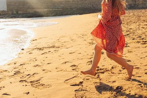 Girl runs on beach as waves crash in background during  sunny afternoon outin Stock Photos