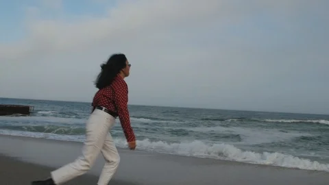 Girl runs on the waves in shoes Stock Footage 102016053