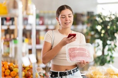 Girl scan QR-code on raw beef tenderloin package in store Stock-Fotos