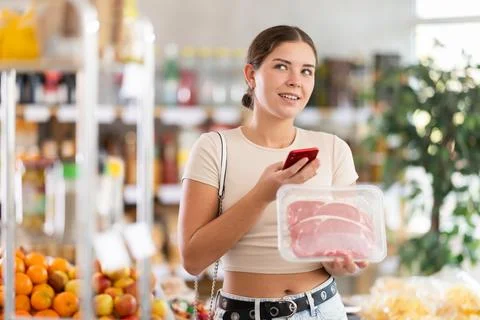 Girl scan QR-code on raw beef tenderloin package in store Stock-Fotos