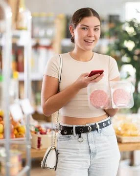 Girl scan QR-code on raw hamburger cutlet package in store Stock-Fotos