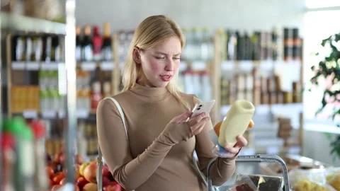 Girl scan QR code, take reading sauce label using phone camera in shop Stock Footage 308419225