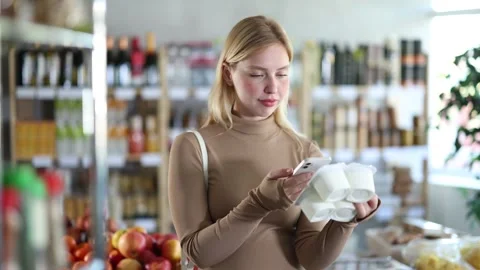 Girl scan QR code, take reading yogurt label using phone camera in shop Stock Footage 315538947