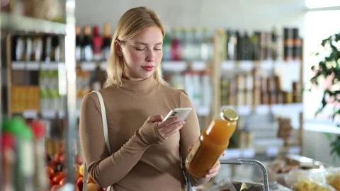 Girl scan QR code, take reading peach juice label using phone camera in shop Stock Footage 343275551