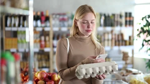Girl scan QR code, take reading eggs label using phone camera in shop Stock Footage 344845744