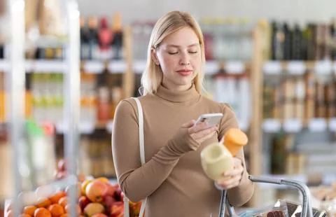 Girl scan QR code, take reading sauce label using phone camera in shop Stock Photos