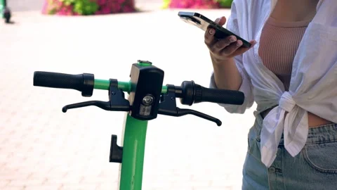 The girl scans the code of the electric scooter for rent. Street sports Stock Footage 248841527