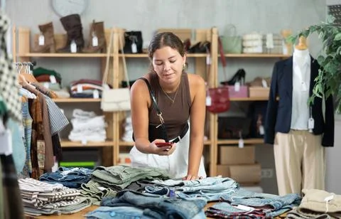 Girl scans QR code and label of denim jeans using mobile phone camera. Stock-Fotos