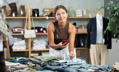 Girl scans QR code and label of denim jeans using mobile phone camera. Stock-Fotos