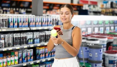 Girl scans QR code with her phone to check product information. Buying cans of Stock Photos