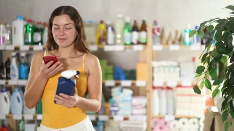 Girl scans QR code on label of window and glass cleaning spray in supermarket Stock Footage 313457464