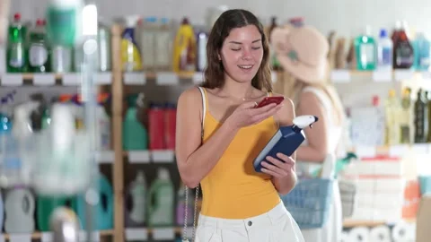 Girl scans QR code on label of window and glass cleaning spray in supermarket Stock Footage 331308102
