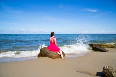 Girl in a scarlet dress by the sea. Wind, waves, deserted beach Stock Photos