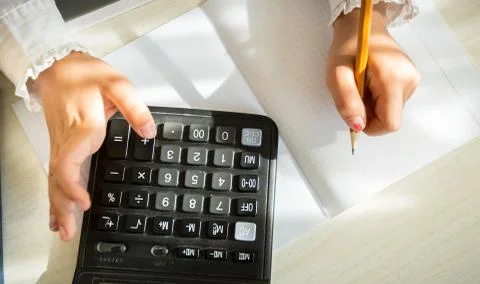 Girl in school uniform solving task with help of calculator Stock Photos
