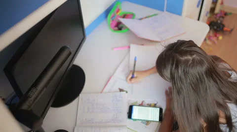 Girl schoolgirl doing homework. Girl learns lessons. using smartphone Stock Footage