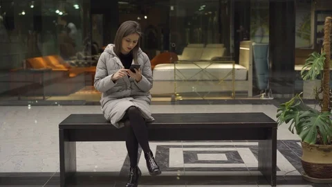 Girl scrolling on smartphone while sitting on bench and talking to boyfriend 스톡 동영상 124704391