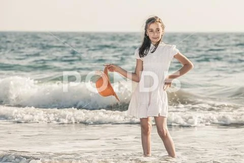 Girl on the seashore wearing an orange hat and a white dress Stock Photos