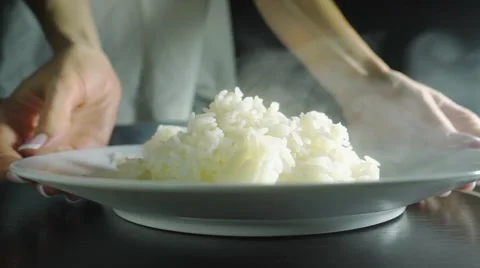 Girl serving steaming plain rice on a plate, close up slow motion video Stock Footage 59430964