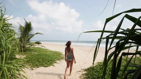 Girl setting on a deserted sandy beach through the thorns Stock Footage 76941387