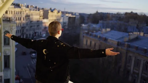 Girl with shaved head stands on the balcony of the house 스톡 동영상 129973953