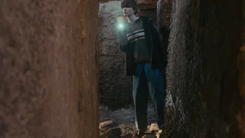 Girl Shining Flashlight between Narrow Passage in Wall Stock Footage 250957864