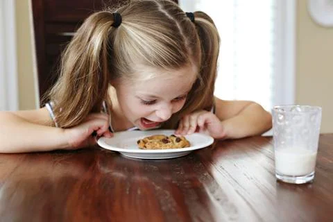 Girl shouting at cookie on table Stock Photos