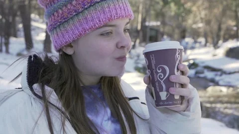 Girl sips coffee down next to stream, smiling looking up Video stock 168489848