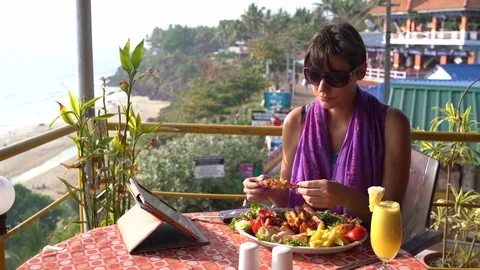 A girl sits in a cafe and eats shrimp with her hands Video stock 74657956